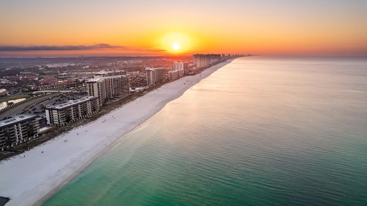 Aerial view of Panama City Beach at sunset featuring beachfront condos and coastline, ideal for Panama City Beach rentals