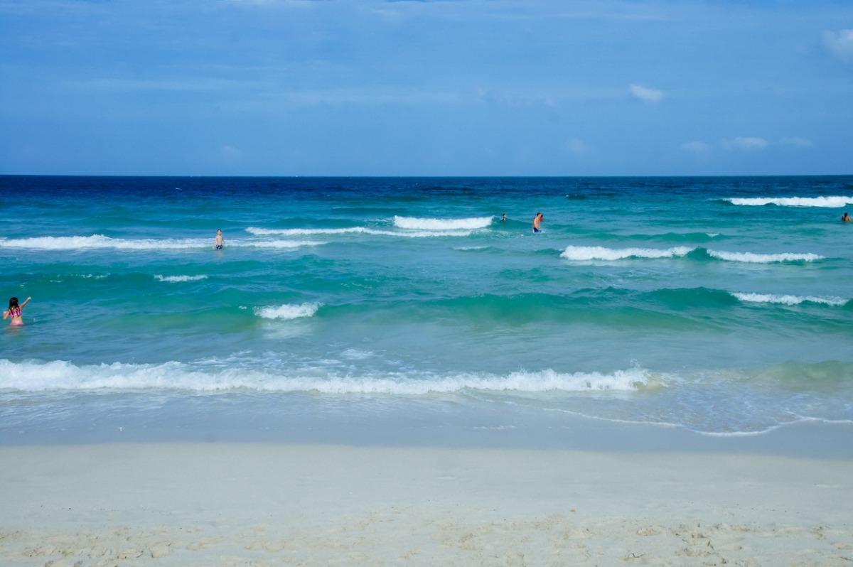 Guests enjoying the Gulf waters near Sunrise Beach Condos in Panama City Beach with clear emerald waves and white sand shoreline
